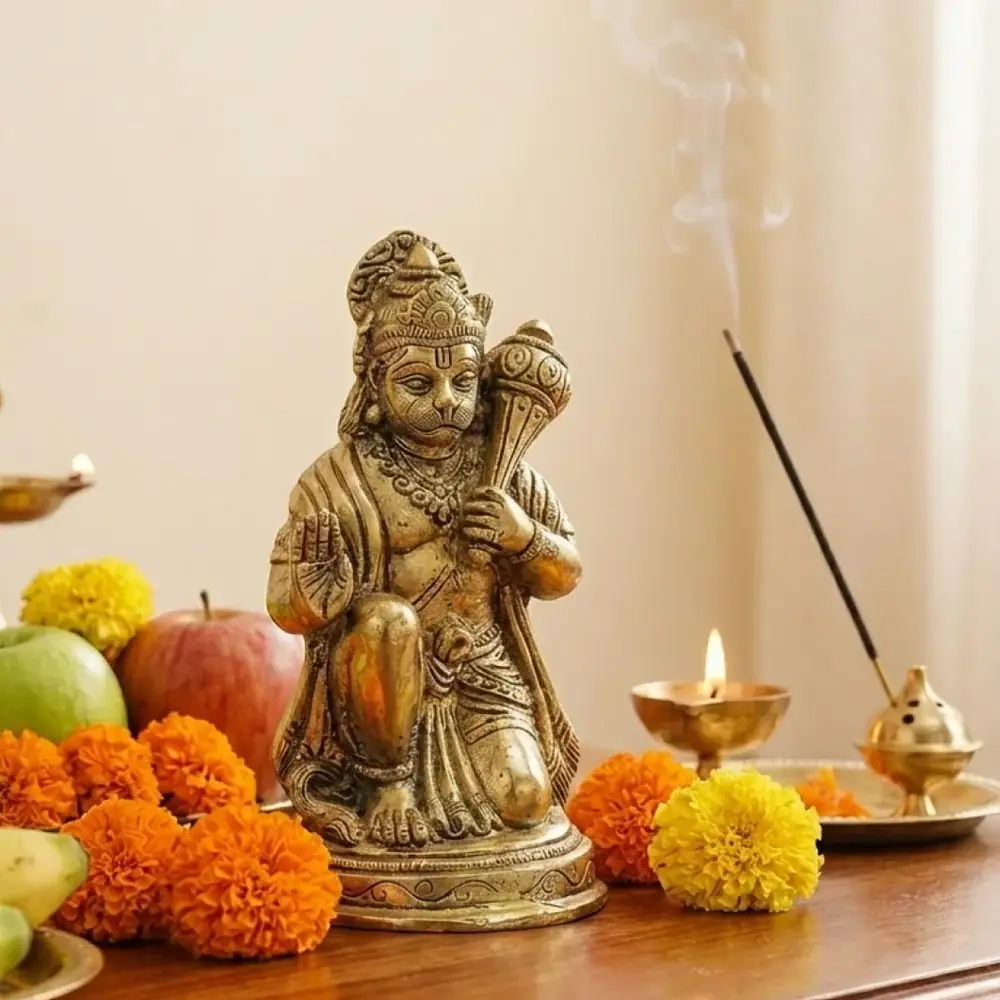 Seated brass Hanuman with a mace, among fruit, flowers and a lamp