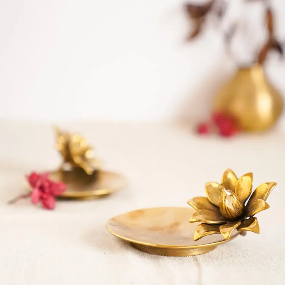 Two small brass lotus plates among flowers