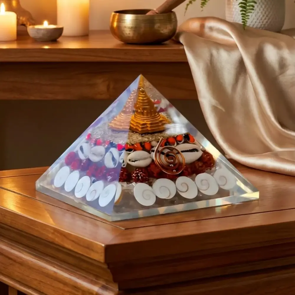 Clear pyramid with a yantra and cowrie shells on a wooden table