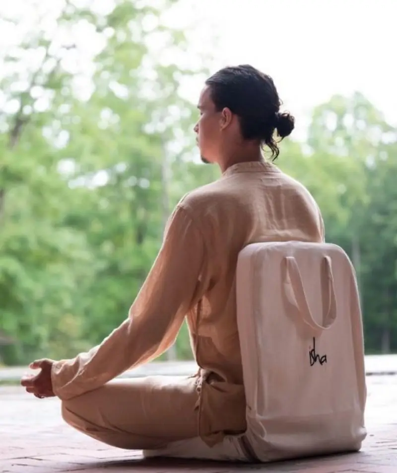 Person sitting cross-legged on the chair in a garden, carrying it on their back