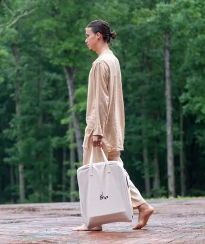 Person walking in a forest with the chair on their shoulder