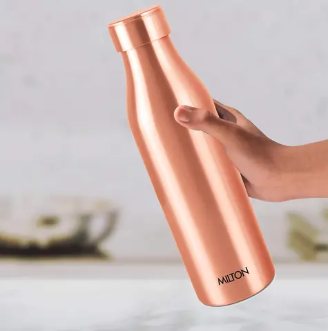 A hand holding the copper bottle