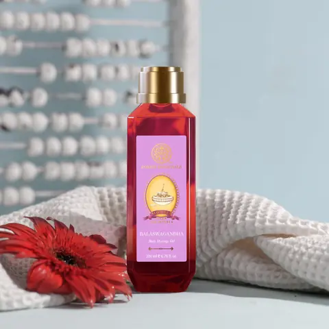 The bottle beside a white towel and a red flower