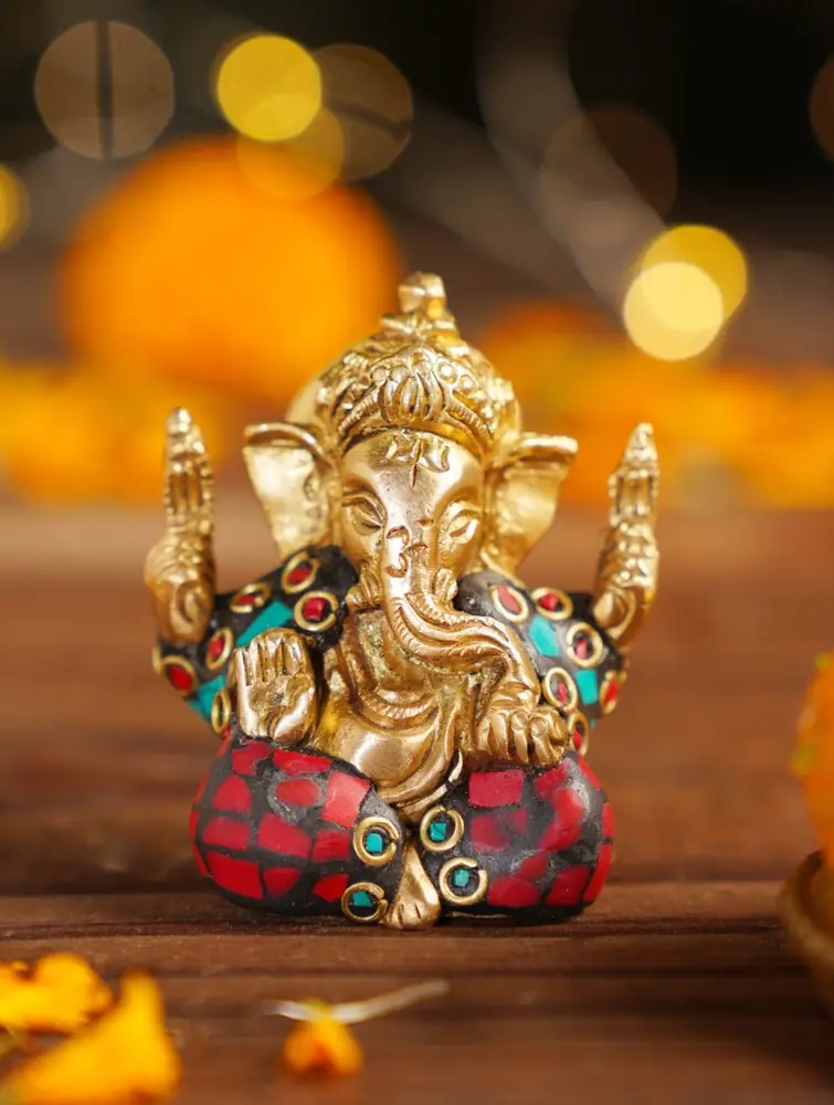 Seated brass Ganesha with coloured inlay among marigolds