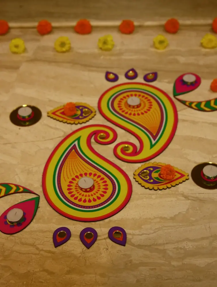 Colourful MDF rangoli pieces on a floor with a small lamp