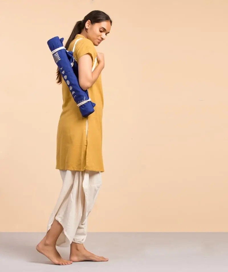 Person carrying a rolled blue Mystical meditation mat on their shoulder