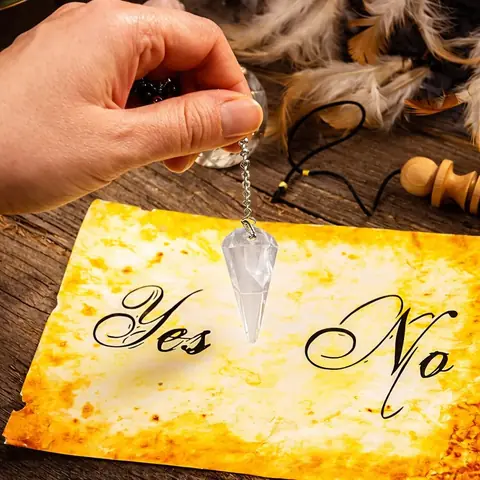 A pendulum held over a yes and no card