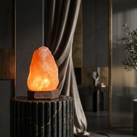 A lit salt lamp on a dark table beside a curtain