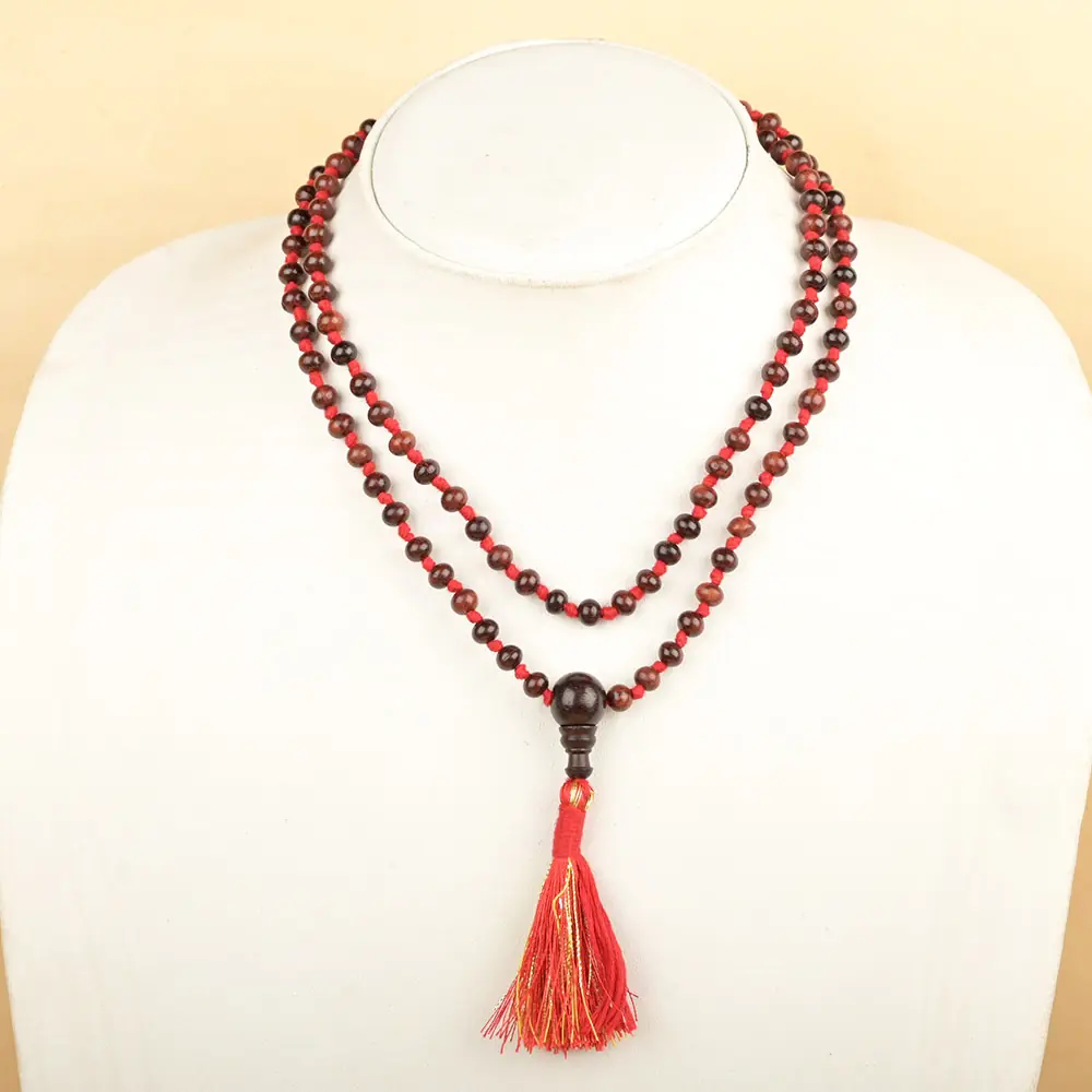 Red sandalwood mala with a red tassel on a white display bust