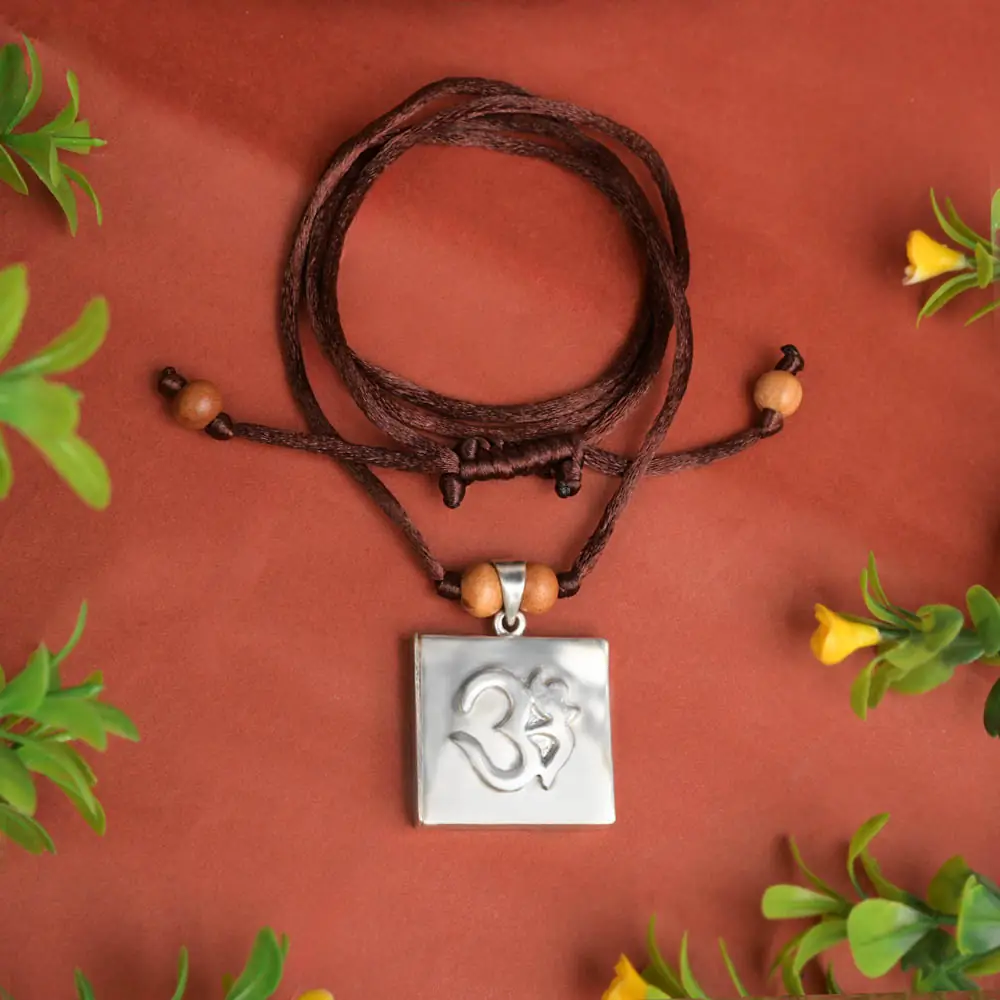 Silver square pendant with an Om on a brown cord