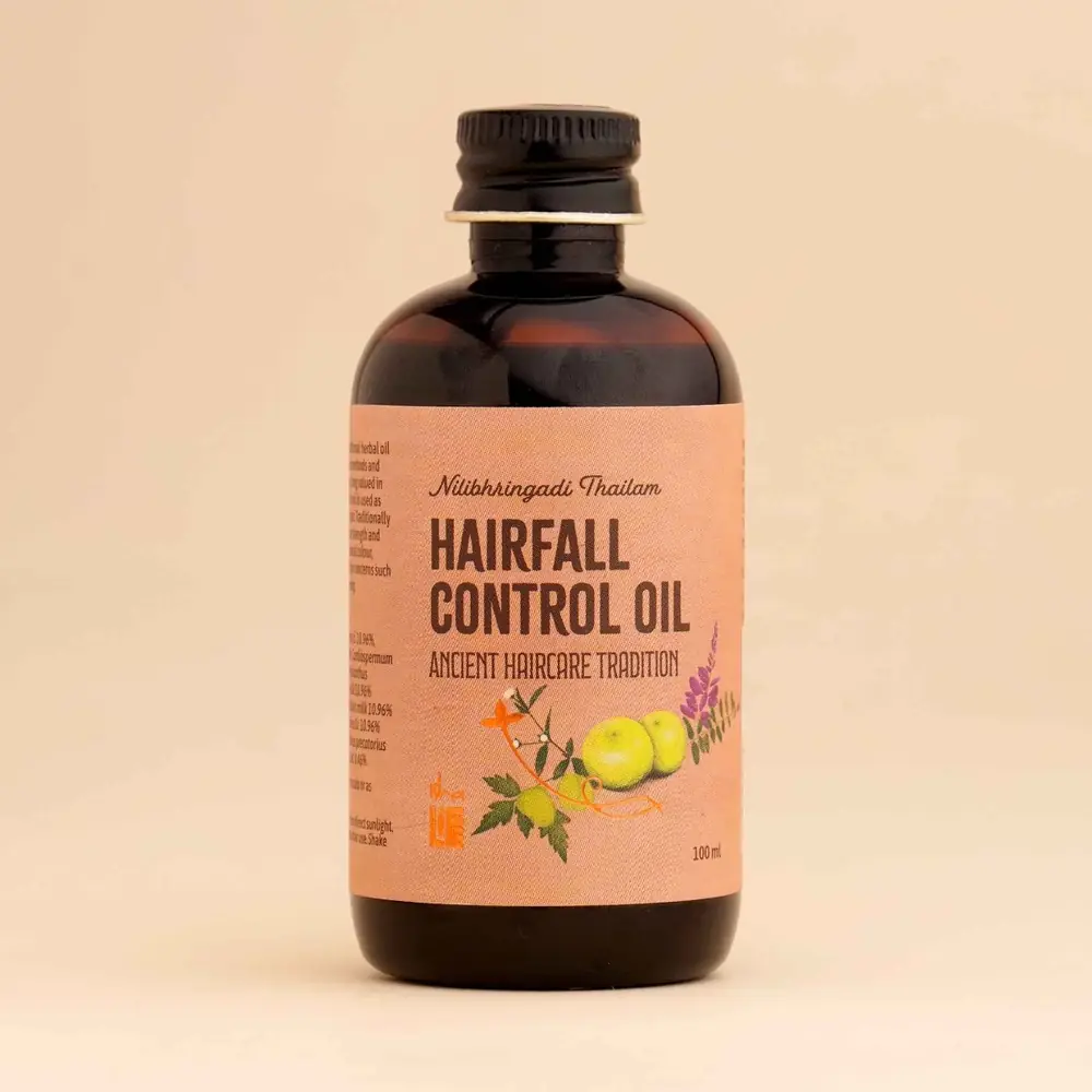 Herbal hair oil bottle beside herbs and amla