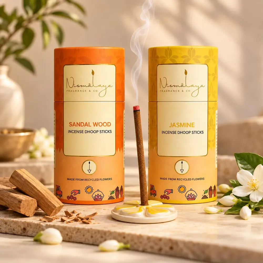 Two Nirmalaya tubes, sandalwood and jasmine, with a lit stick