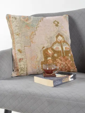 The cover on a grey sofa with a book and a cup