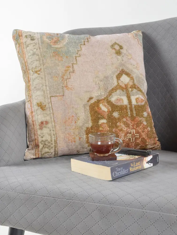 The cover on a grey sofa with a book and a cup