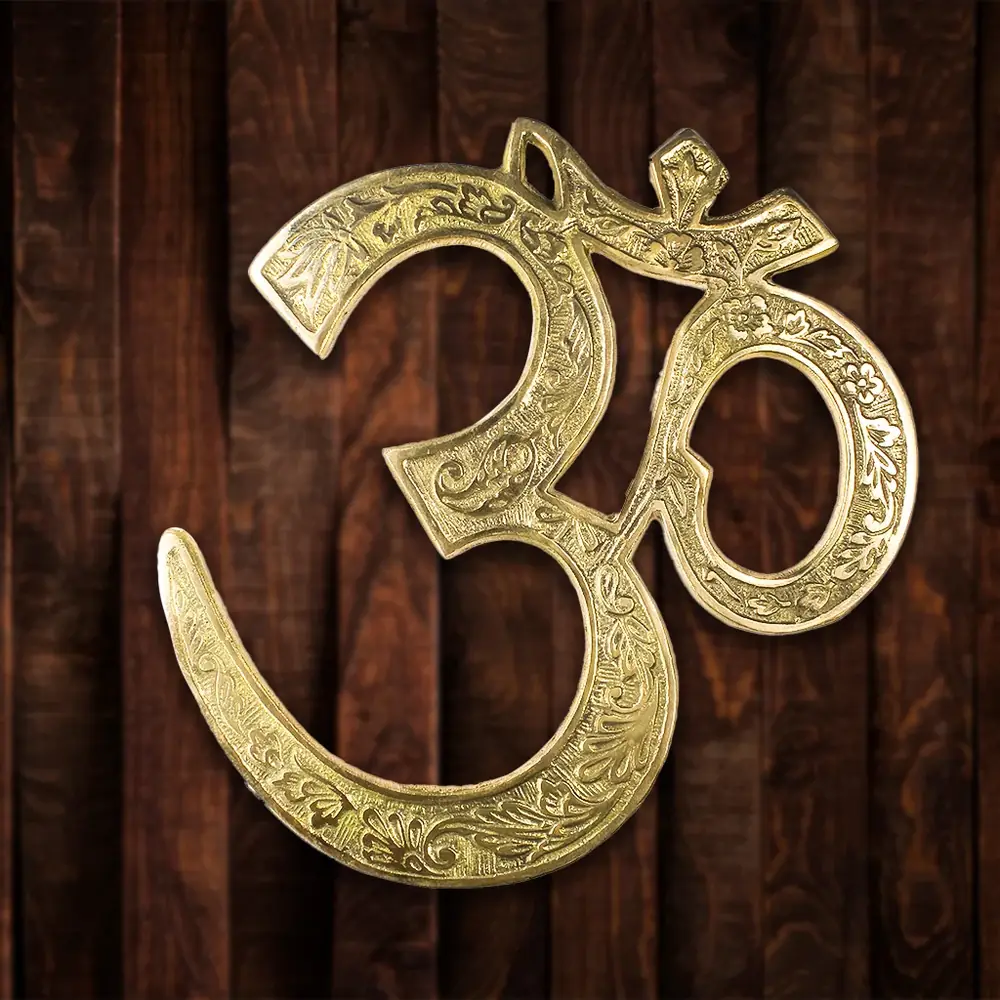 Brass Om hanging on a dark wood panel