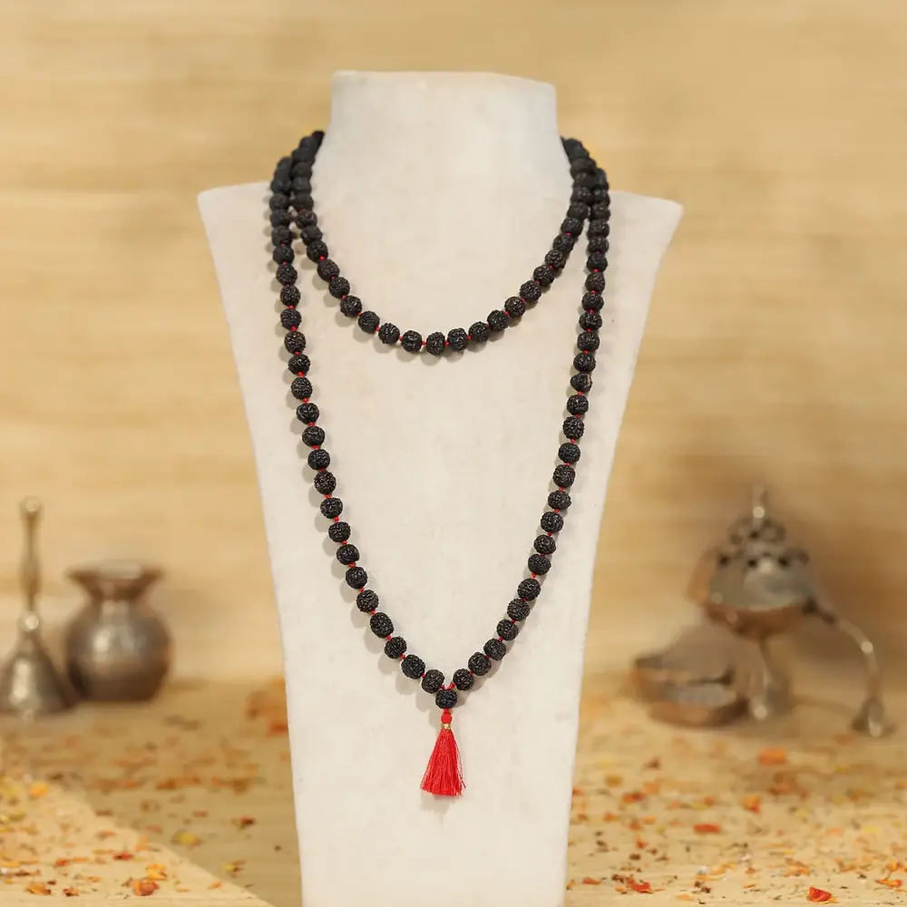 Black rudraksha mala on a display bust with small brass objects