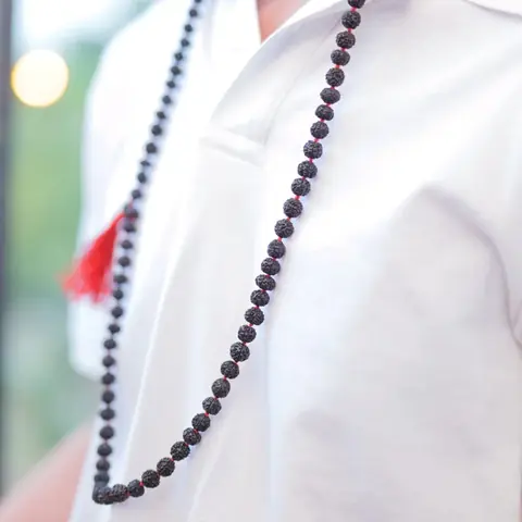 A man wearing the black mala over a white shirt