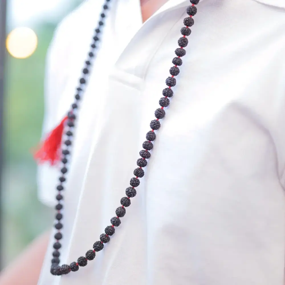 A man wearing the black mala over a white shirt
