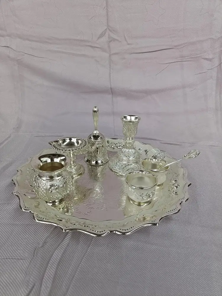 The full silver coloured pooja thali set on a grey cloth
