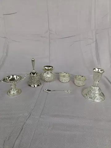 Small silver coloured vessels, bowls and a spoon laid out