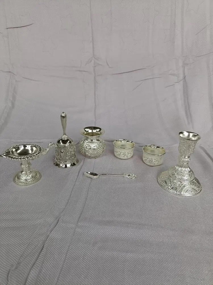 Small silver coloured vessels, bowls and a spoon laid out