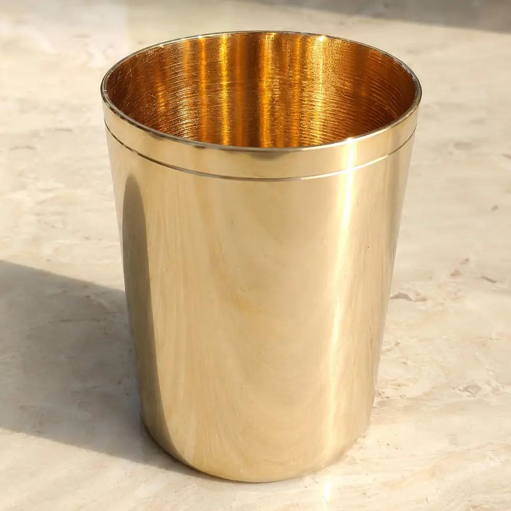 Gold coloured kansa glass on a stone surface