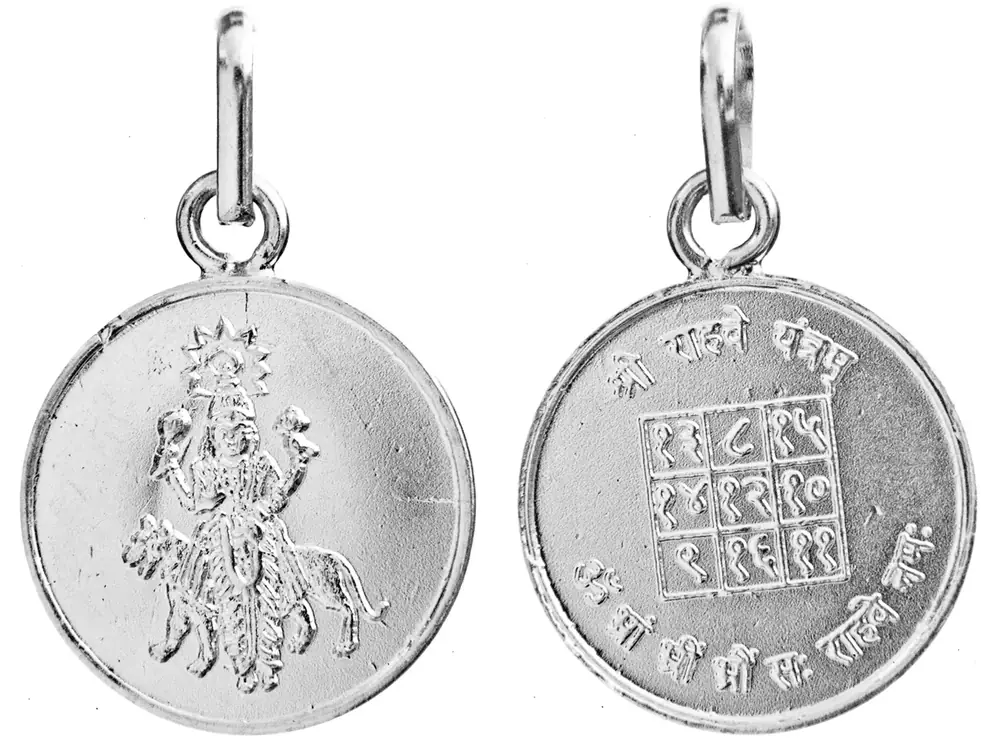 Front and reverse of a round silver Rahu pendant with its yantra