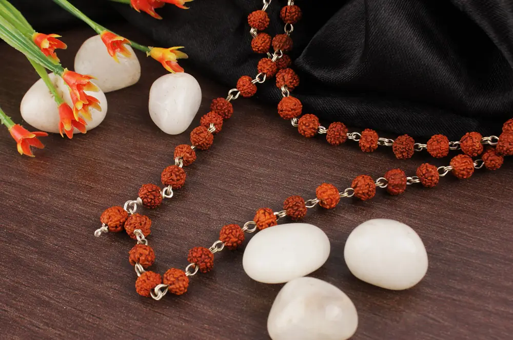 Rudraksha mala on dark cloth with white flowers and stones
