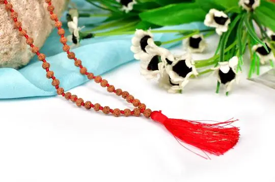 Rudraksha mala with a red tassel on turquoise cloth