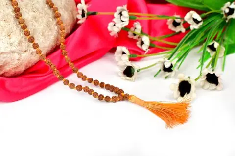 The mala with an orange tassel on pink cloth