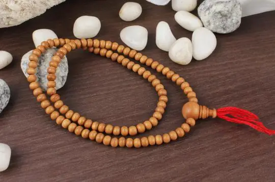 Mala on a dark wood board with stones and a red cord