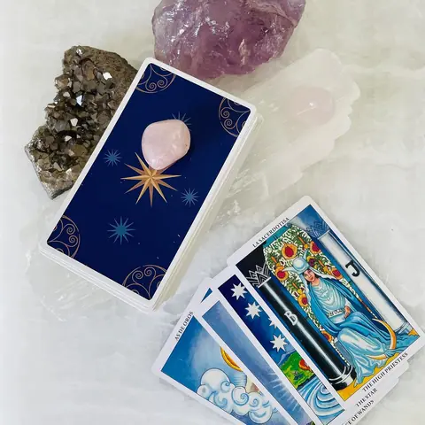 Selenite stick beside tarot cards and crystals
