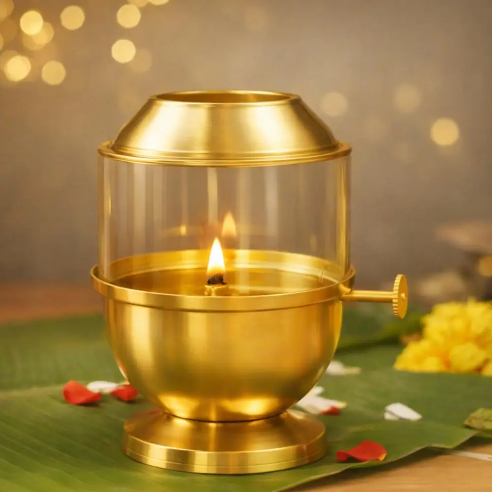 Lit brass Akhand diya with a glass cover on a green leaf with petals