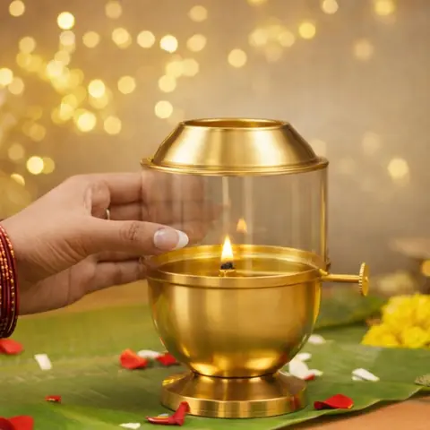 A hand lifting the glass cover from the brass lamp