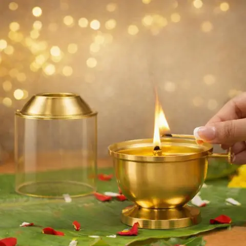 A hand lighting the wick with the glass cover raised
