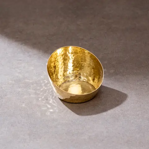 A single hammered brass tea light holder in close view