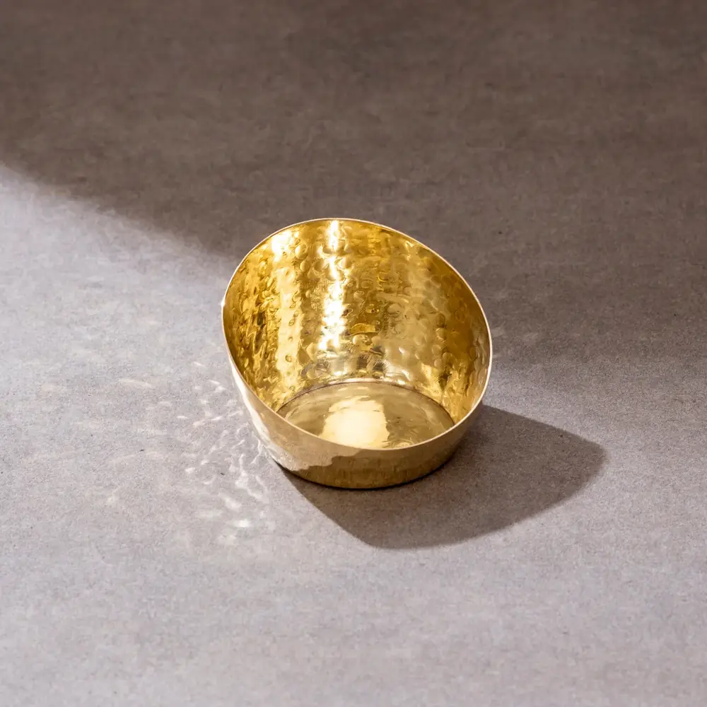 A single hammered brass tea light holder in close view