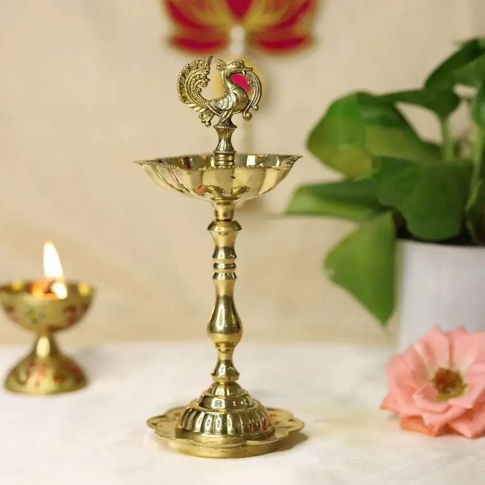 Brass seven wick peacock lamp beside a small diya