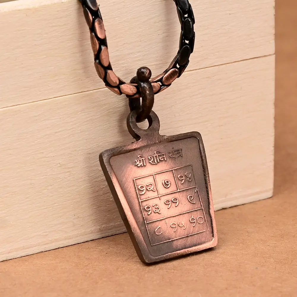 Shani yantra side of the copper locket leaning on a box