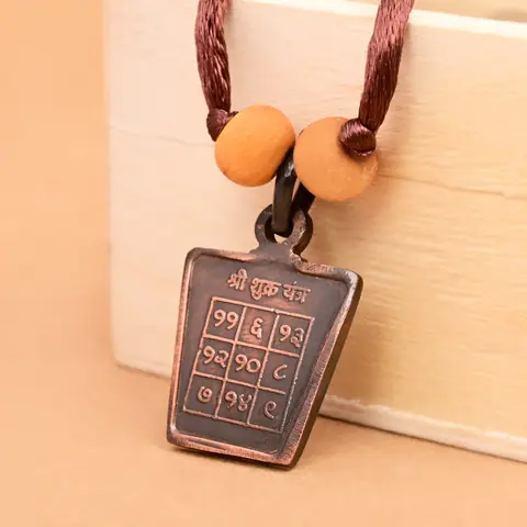 The yantra side on a brown cord with two beads