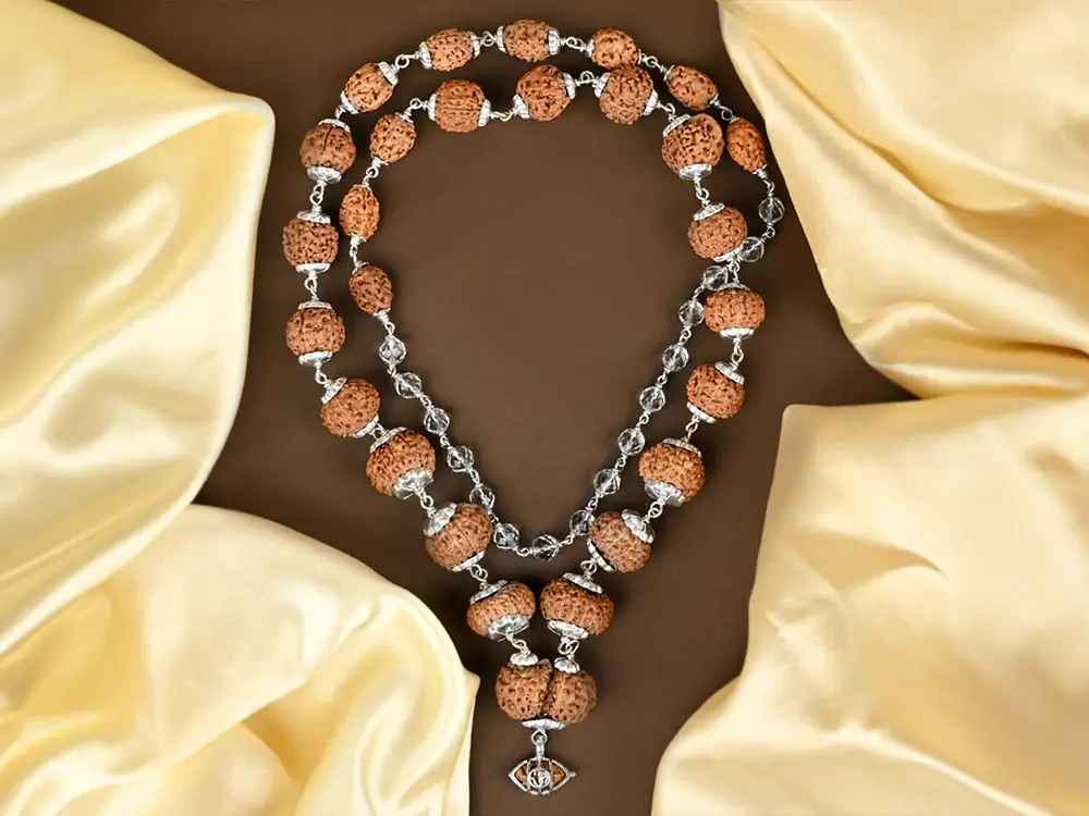Siddha mala with silver capped beads laid on cream and brown cloth