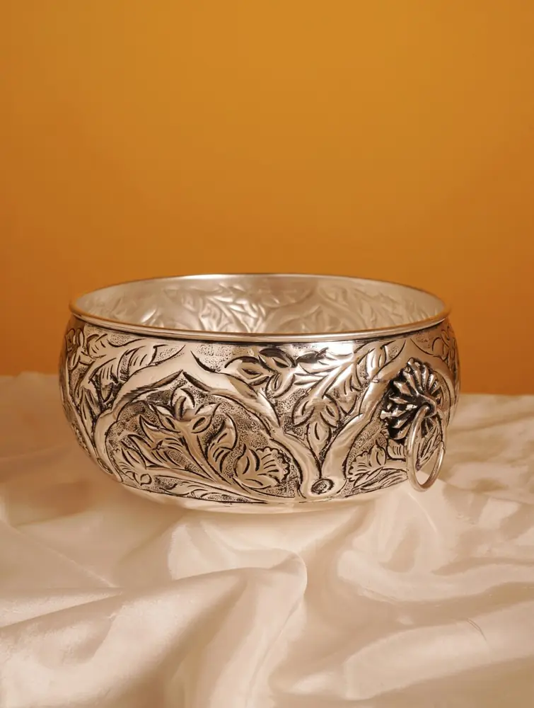 Silver finish etched urli with ring handles on cloth