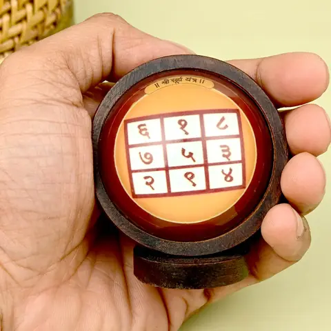 The framed yantra held in a hand for scale
