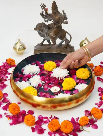 A hand arranging flowers in the urli