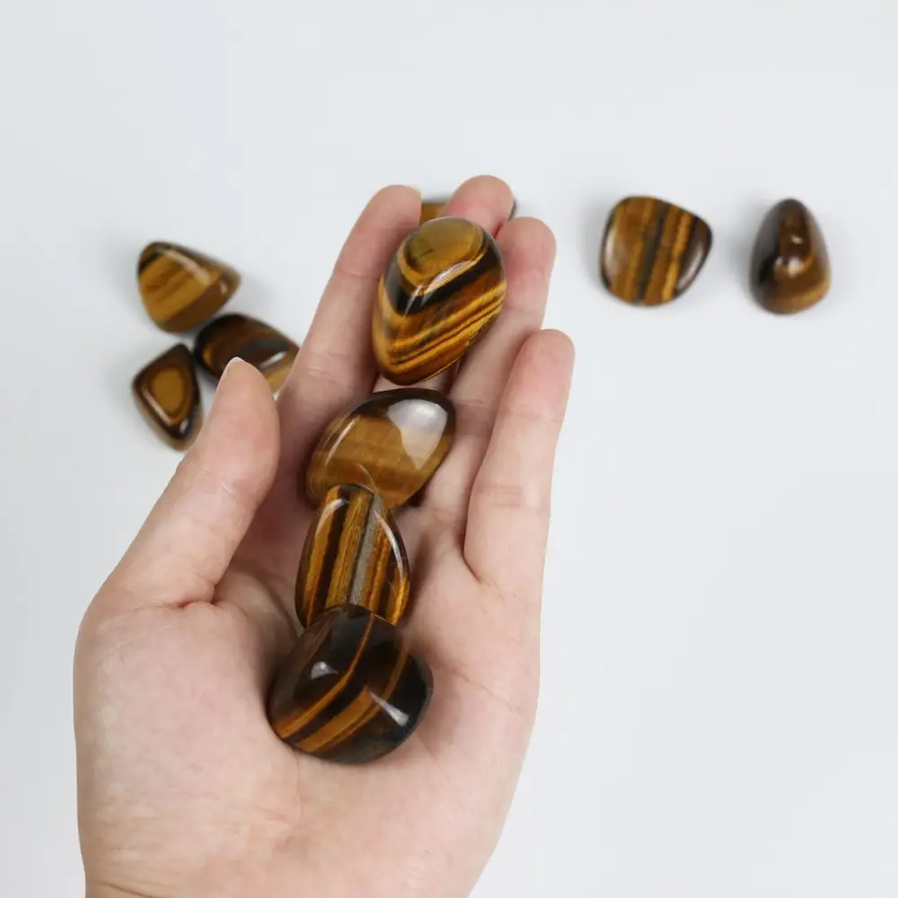 A hand holding several tiger's eye stones