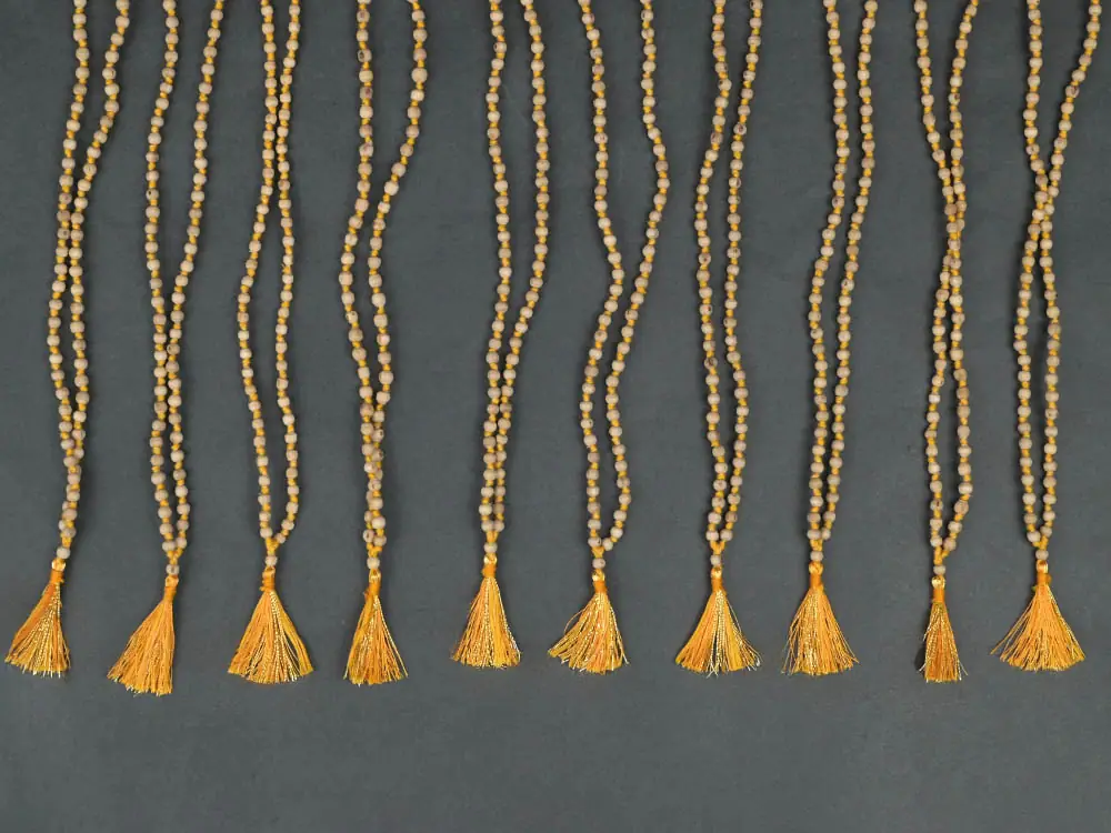 Close view of a tulsi mala with an orange tassel on a dark ground