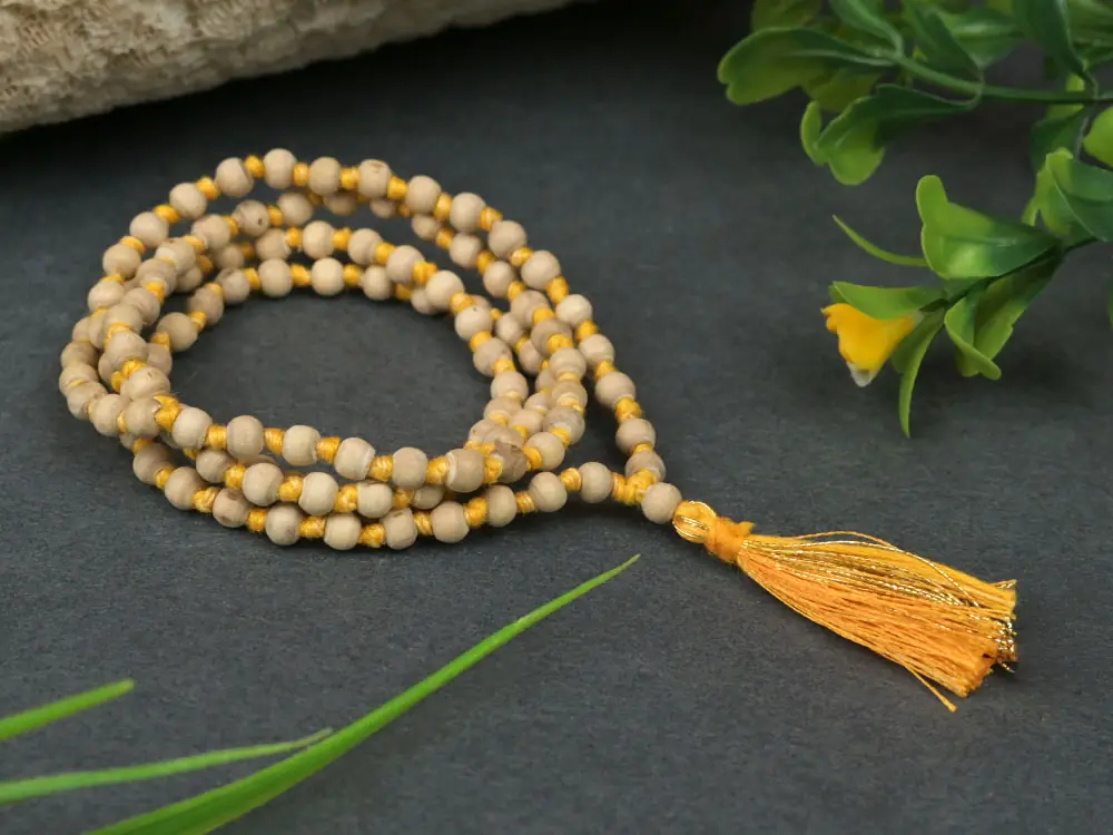 A mala coiled with its tassel beside a log