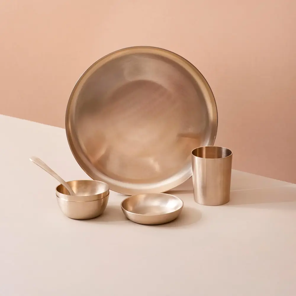A plate with bowls, glass and spoons set for one person