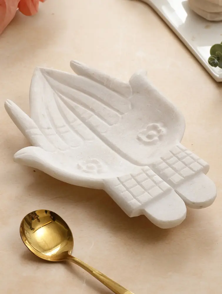 Hand-shaped white marble dish holding muffins and fruit