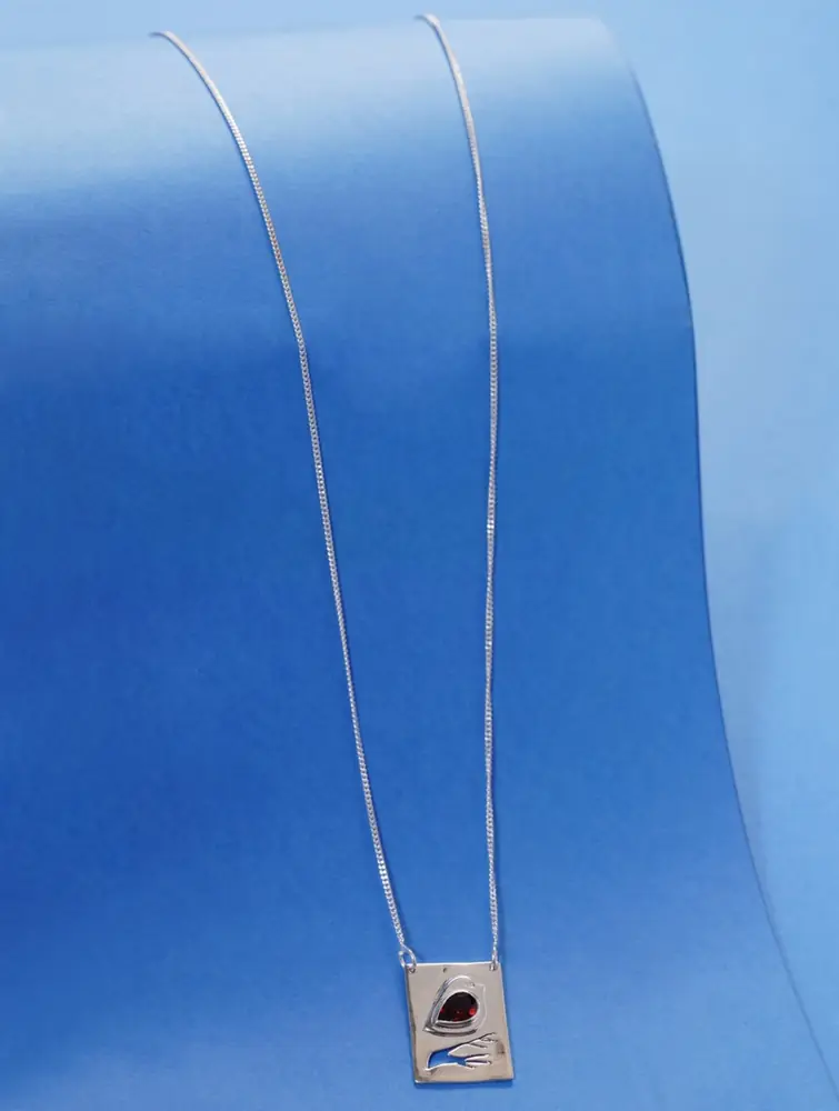 Long silver chain with a square pendant on a blue ground